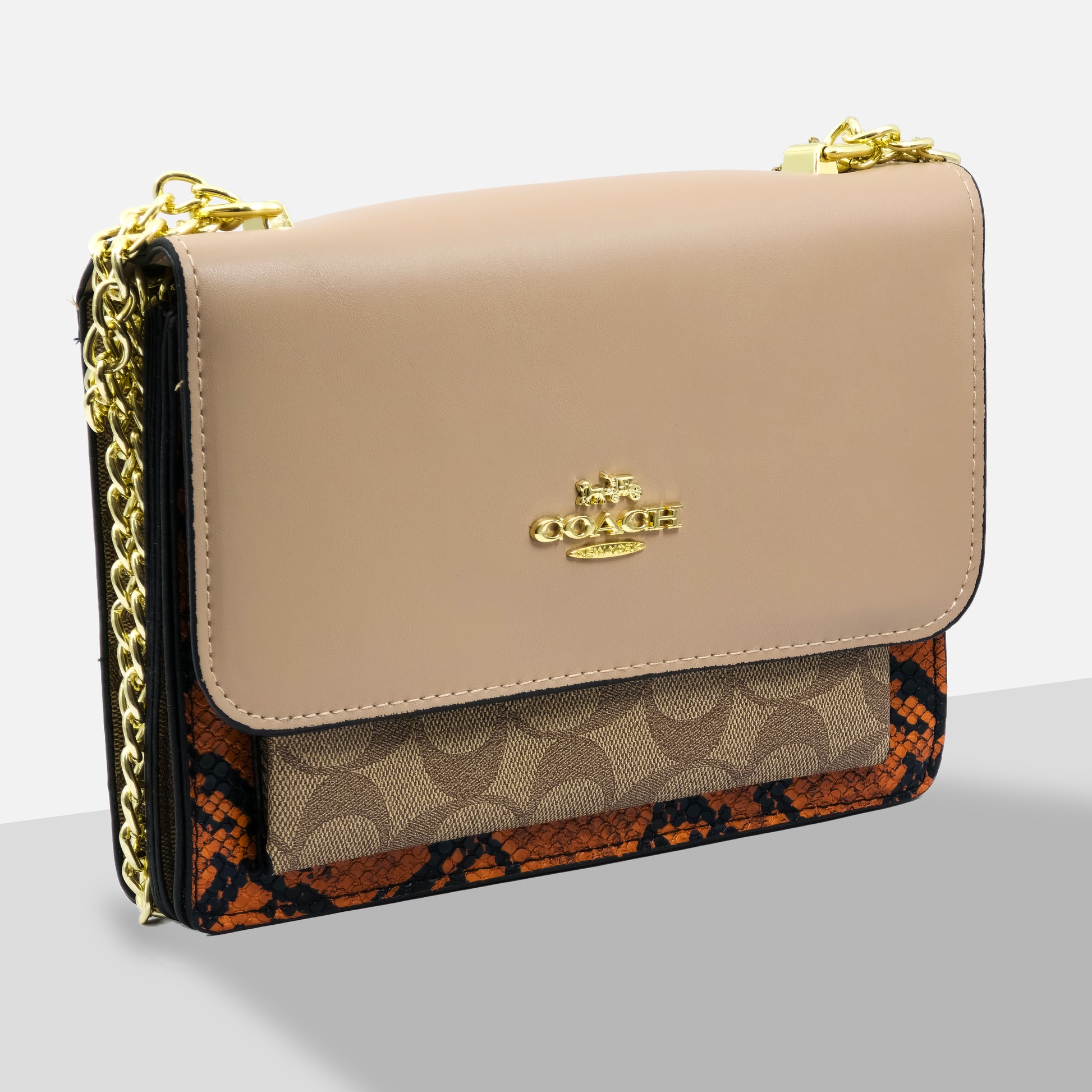 Beige handbag with gold chain strap and Coach logo on a light gray background