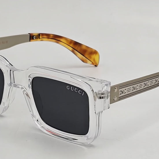 A pair of Gucci stylish sunglasses with a clear frame and dark lenses, featuring the brand's logo on the side.