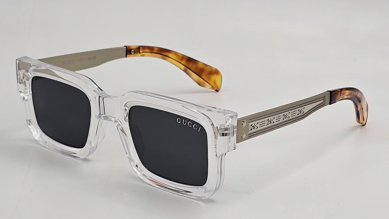 A pair of Gucci stylish sunglasses with a clear frame and dark lenses, featuring the brand's logo on the side.